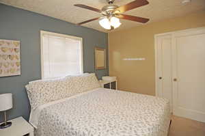 Carpeted bedroom with ceiling fan and a textured ceiling