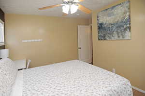 Carpeted bedroom featuring a textured ceiling and ceiling fan