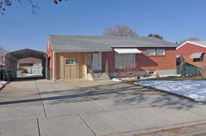 View of front of house with a storage unit and a carport