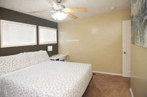 Bedroom with ceiling fan, carpet floors, and a textured ceiling