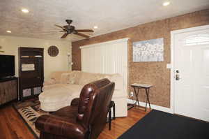 Living room featuring hardwood / wood-style flooring, a textured ceiling, and ceiling fan