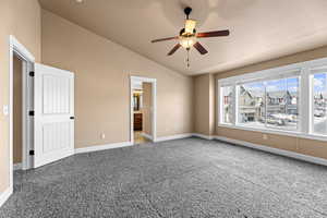 Unfurnished bedroom with vaulted ceiling, ceiling fan, ensuite bathroom, and carpet floors