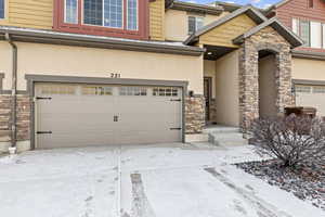 Snow covered property entrance featuring a garage