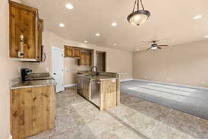 Kitchen featuring ceiling fan, a kitchen island with sink, pendant lighting, stainless steel dishwasher, and sink