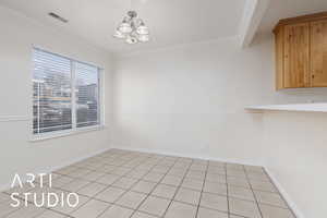 Unfurnished dining area with light tile patterned floors, a notable chandelier, and ornamental molding