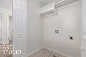 Laundry area featuring light tile patterned floors, hookup for a washing machine, and electric dryer hookup