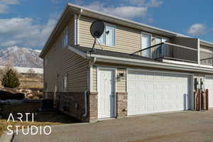 View of side of property with cooling unit, a garage, a mountain view, and a balcony