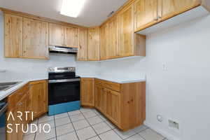 Kitchen featuring electric stove, light tile patterned floors, and sink