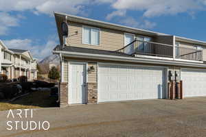 View of front of property featuring a balcony, central AC unit, a garage, and a mountain view