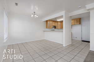 Interior space featuring an inviting chandelier, light tile patterned floors, crown molding, and kitchen peninsula