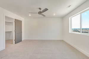 Unfurnished bedroom featuring ceiling fan, light colored carpet, a closet, and a walk in closet