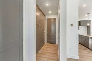 Hallway with sink, light hardwood / wood-style flooring, and wood walls