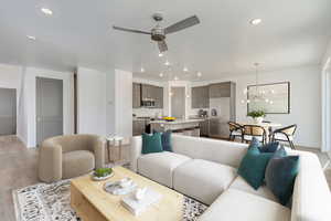 Living room with ceiling fan with notable chandelier, sink, and light hardwood / wood-style floors