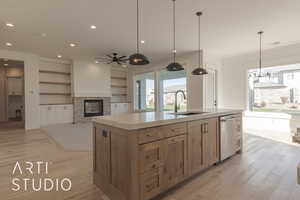 Kitchen with a center island with sink, ceiling fan, a fireplace, dishwasher, and sink