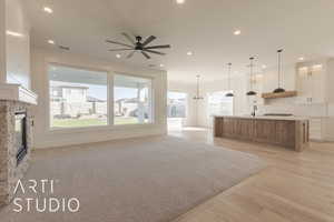 Unfurnished living room featuring ceiling fan, a stone fireplace, and light hardwood / wood-style flooring