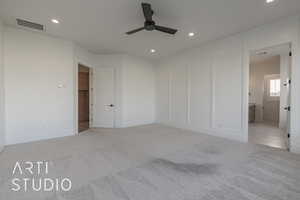 Unfurnished bedroom with ensuite bath, ceiling fan, and light carpet