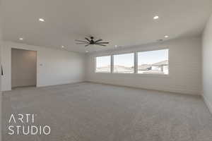 Empty room featuring ceiling fan, a mountain view, and light colored carpet