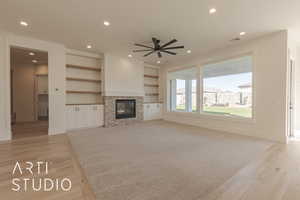 Unfurnished living room featuring ceiling fan, light wood-type flooring, and a fireplace