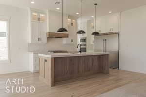 Kitchen with white cabinets, a kitchen island with sink, and built in appliances