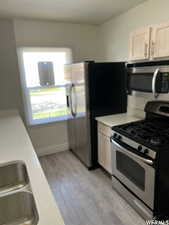 Kitchen with light wood-type flooring, appliances with stainless steel finishes, white cabinets, and sink