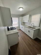 Kitchen featuring range, dark wood-type flooring, white cabinetry, tasteful backsplash, and sink