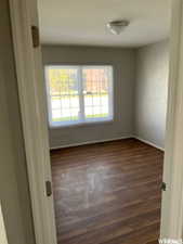 Empty room featuring a healthy amount of sunlight and dark wood-type flooring