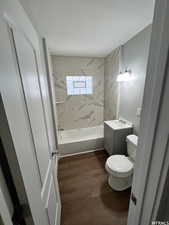 Full bathroom featuring toilet, vanity, tiled shower / bath combo, and hardwood / wood-style floors