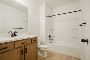 Full bathroom with toilet, hardwood / wood-style flooring, vanity, and bathtub / shower combination
