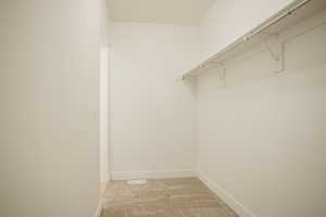 Walk in closet with light colored carpet
