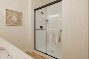 Bathroom featuring a sink, baseboards, a stall shower, and wood finished floors