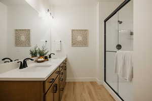Bathroom featuring a shower stall, wood finished floors, and a sink