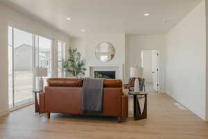 Living room featuring light wood-type flooring, a fireplace, baseboards, and recessed lighting