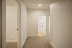 Corridor featuring light carpet