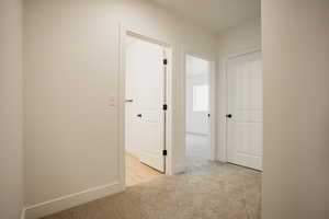 Corridor featuring light colored carpet