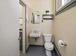 Bathroom featuring toilet, concrete flooring, and sink