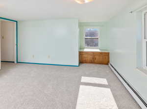 Unfurnished bedroom featuring baseboard heating and light colored carpet