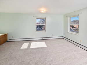 Spare room with light carpet and a baseboard heating unit