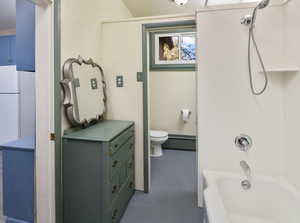 Bathroom featuring a baseboard heating unit, toilet, and shower / washtub combination