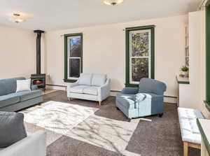 Carpeted living room with a wood stove and a baseboard heating unit