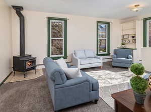 Living room with a wood stove, a wealth of natural light, tile patterned floors, and a baseboard heating unit