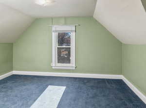 Bonus room with dark carpet and lofted ceiling