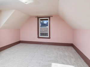 Additional living space with lofted ceiling and light colored carpet