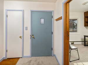 Corridor featuring baseboard heating and light colored carpet