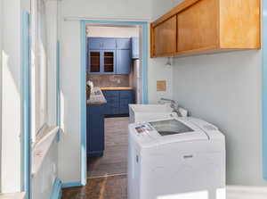 Washroom with cabinets, washing machine and clothes dryer, and sink