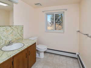 Bathroom featuring baseboard heating, toilet, and vanity