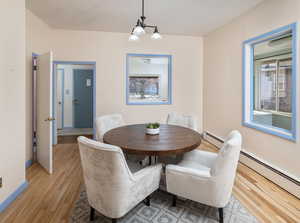 Dining room featuring a baseboard heating unit, light wood-type flooring, and a notable chandelier