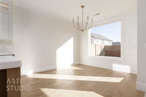 Unfurnished dining area featuring a notable chandelier and light wood-type flooring