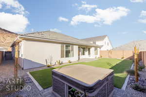 Rear view of house with a patio area, a hot tub, and a lawn