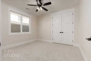 Unfurnished bedroom with ceiling fan, light colored carpet, and a closet