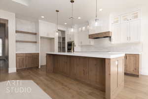 Kitchen with decorative light fixtures, a center island with sink, decorative backsplash, white cabinets, and black electric cooktop